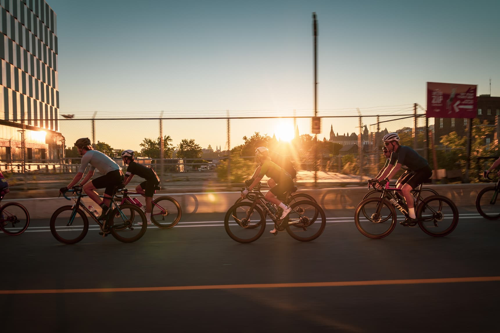 A Common Empire group ride crossing a bridge at sunset in Ottawa