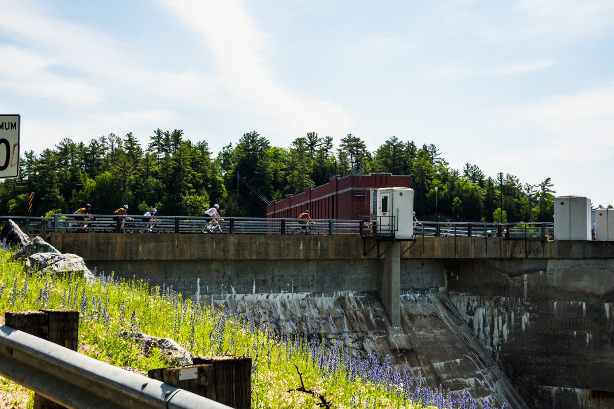 Riders crossing a hydro dam on a country road