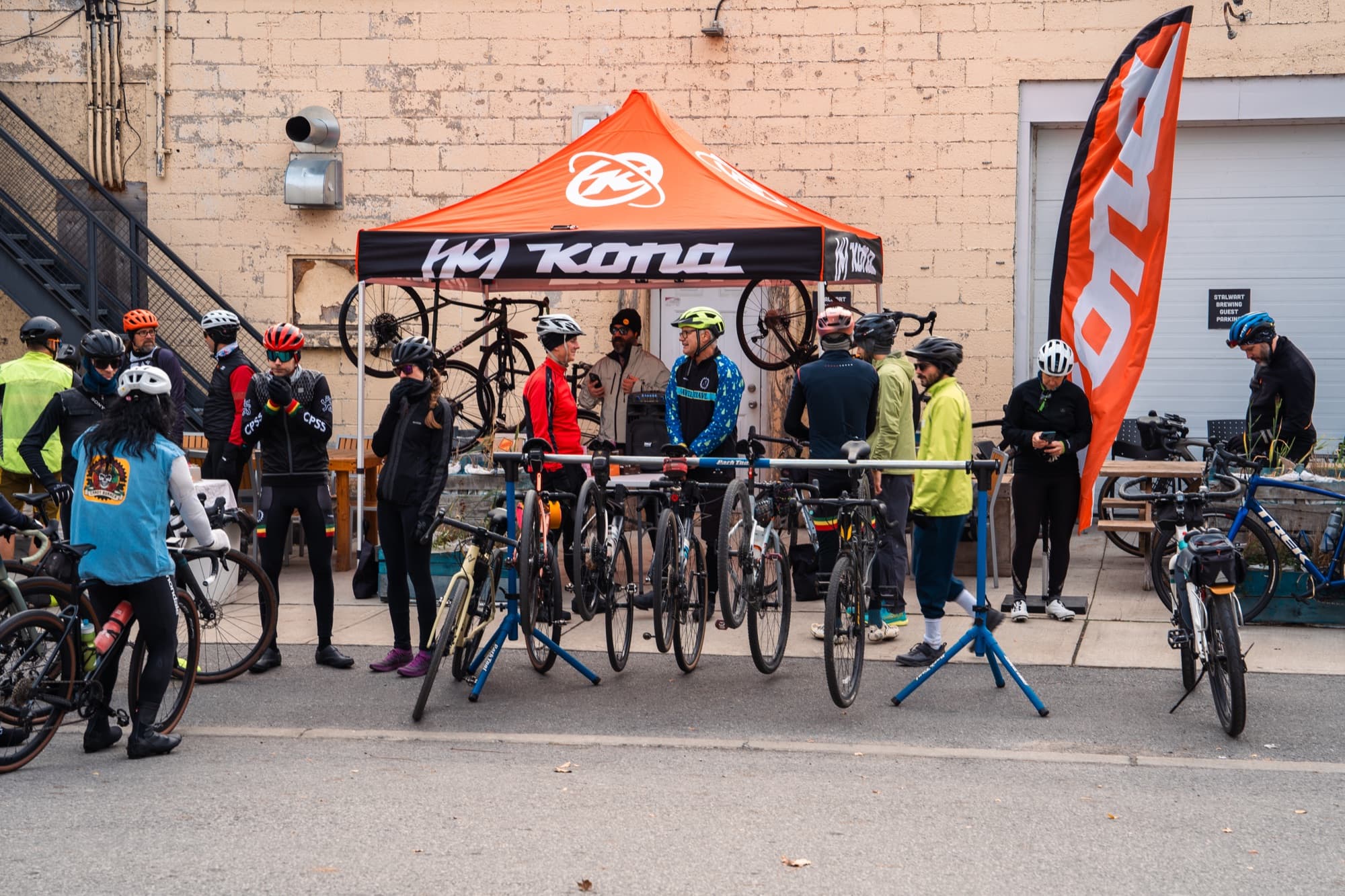 Mechanics checking bikes on stands under a shop tent before a ride
