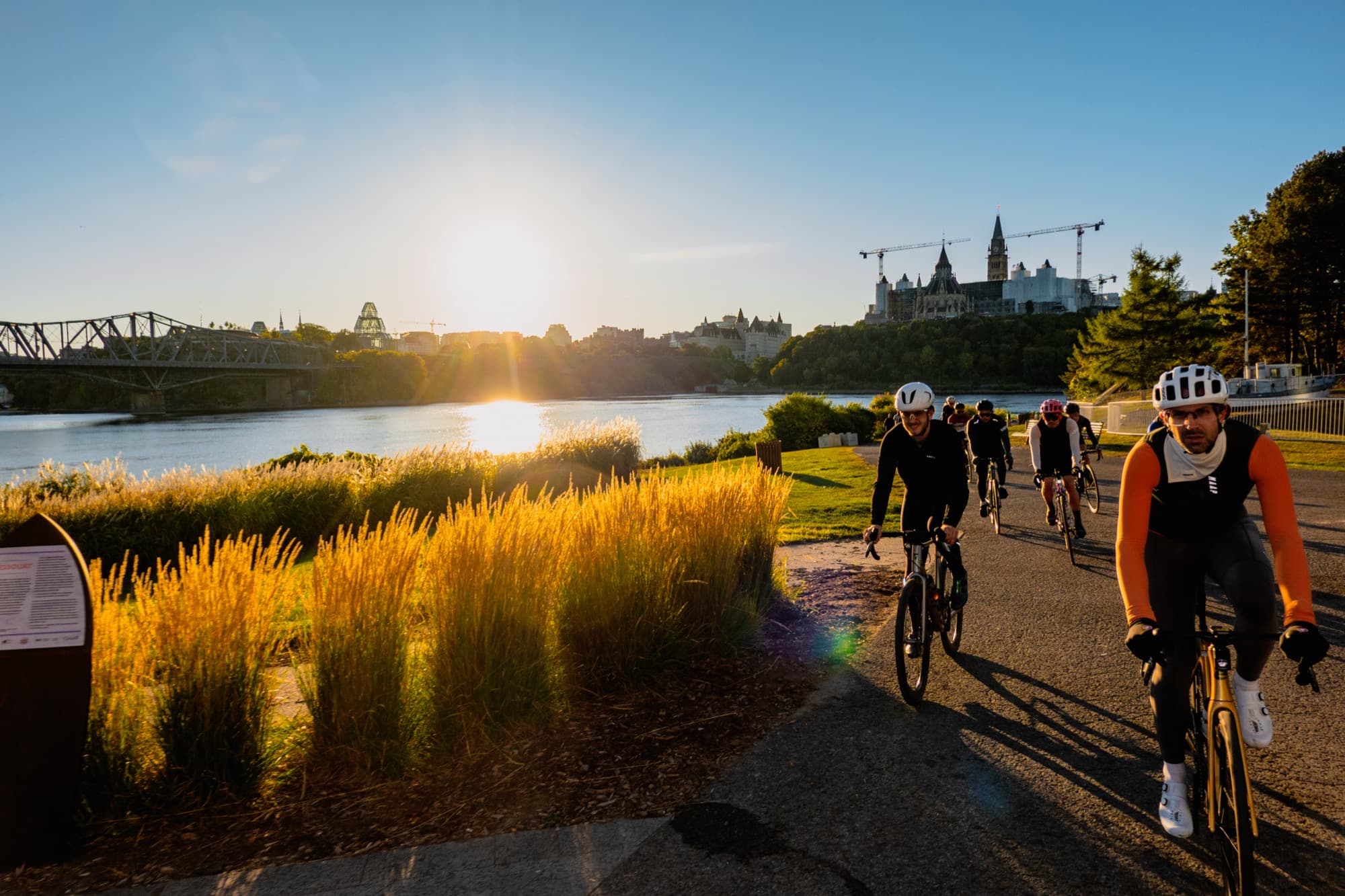Riders on the river pathway at sunrise with Parliament behind