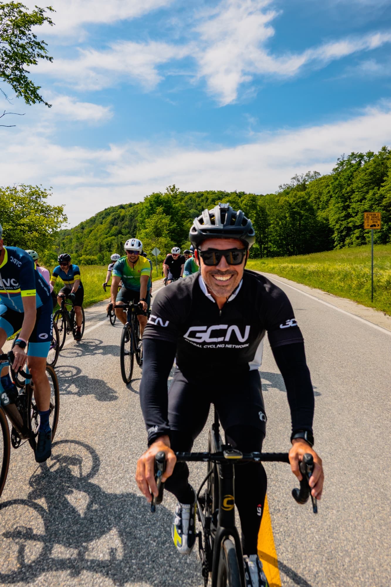 A smiling ride lead at the front of the group on a country road